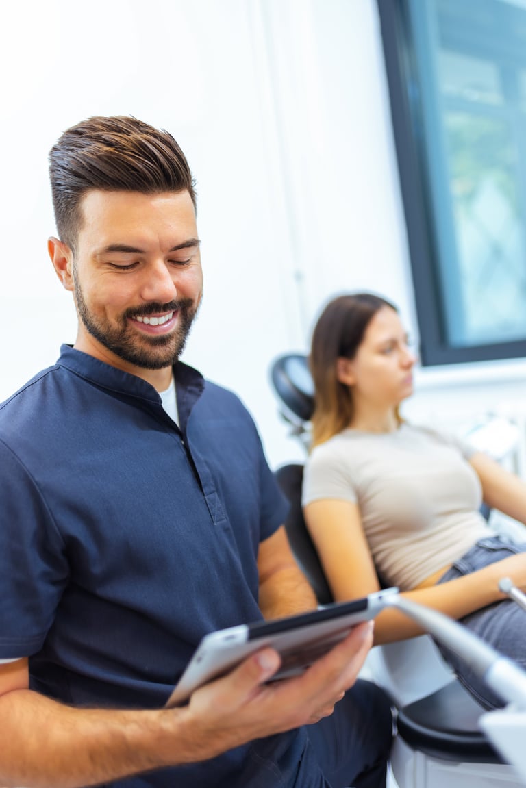 Dentist holding tablet and reviewing treatment plan with patient in dental office