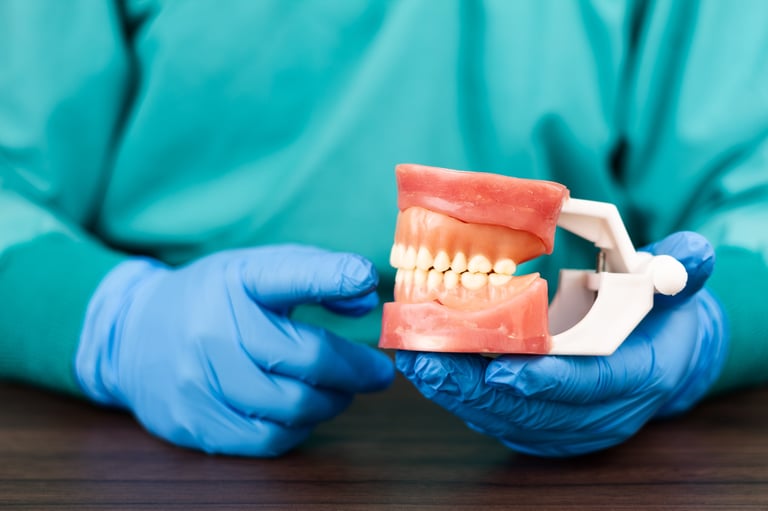 Dentista con guantes azules sosteniendo modelo anatómico de mandíbula con dientes completos, diagnosticando enfermedad periodontal y salud gingival