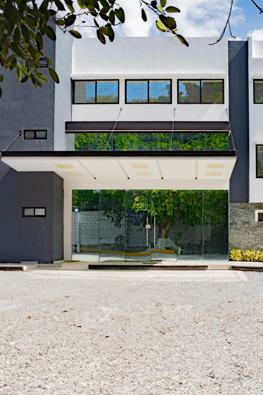 Edificio moderno blanco y negro con ventanas grandes de vidrio y vegetación en balcones