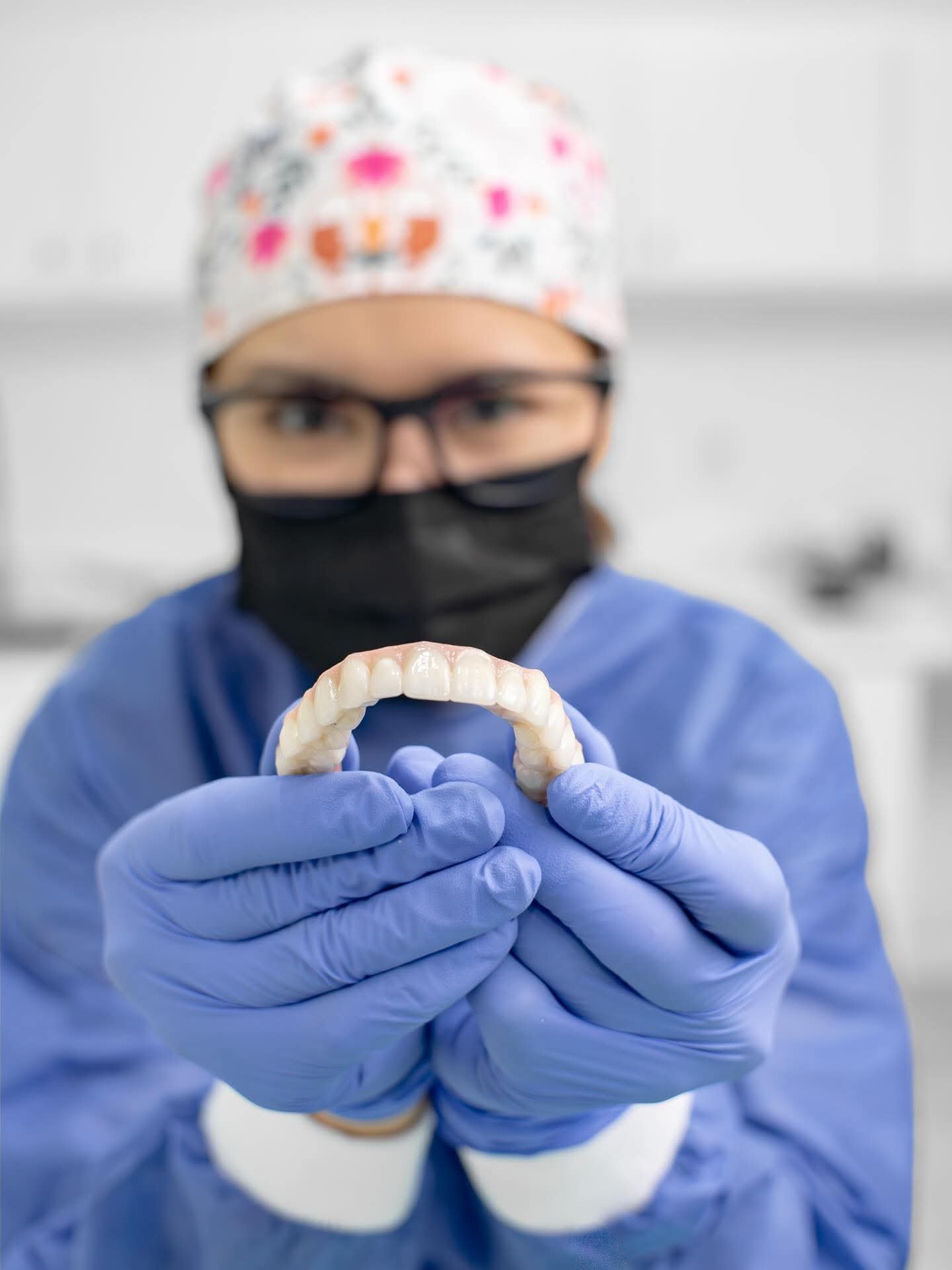 Profesional de la salud con indumentaria quirúrgica sosteniendo modelo dental mostrando dientes